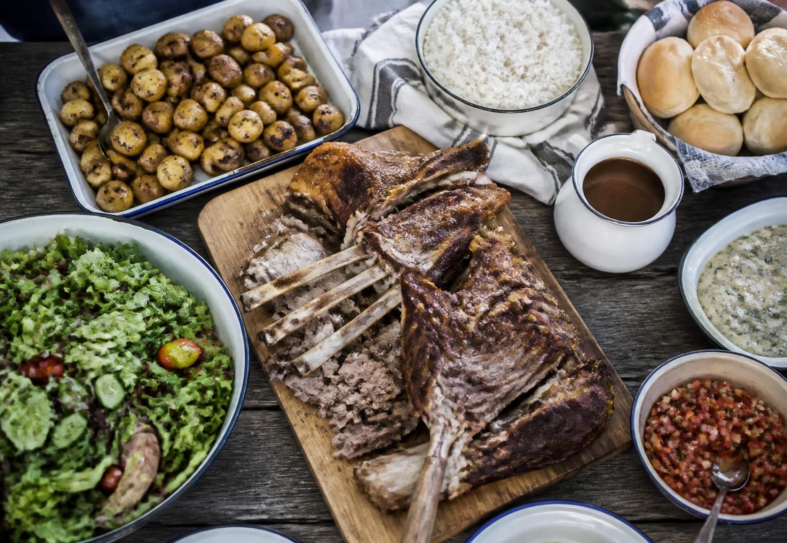 Overhead braai feast table with carved lamb, salads and sides